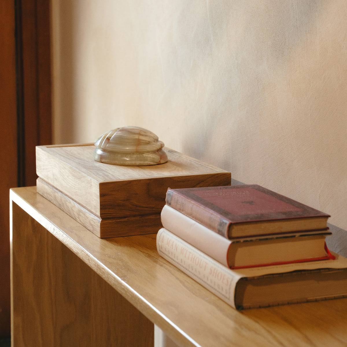Scarab keepsake urn resting on an oak Tray urn beside a stack of books on a wooden console