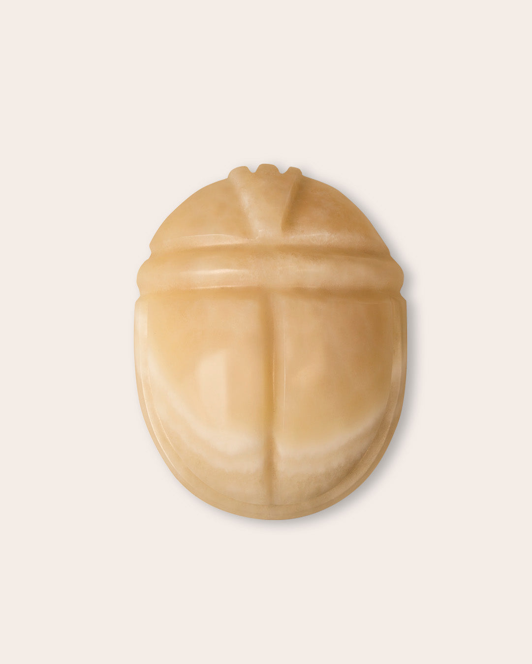 Scarab keepsake urn in honey onyx, top view on a light background