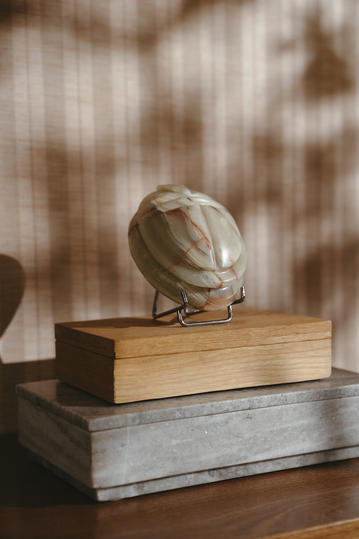 Scarab keepsake urn in jade green onyx on a stand, resting on stacked wooden boxes