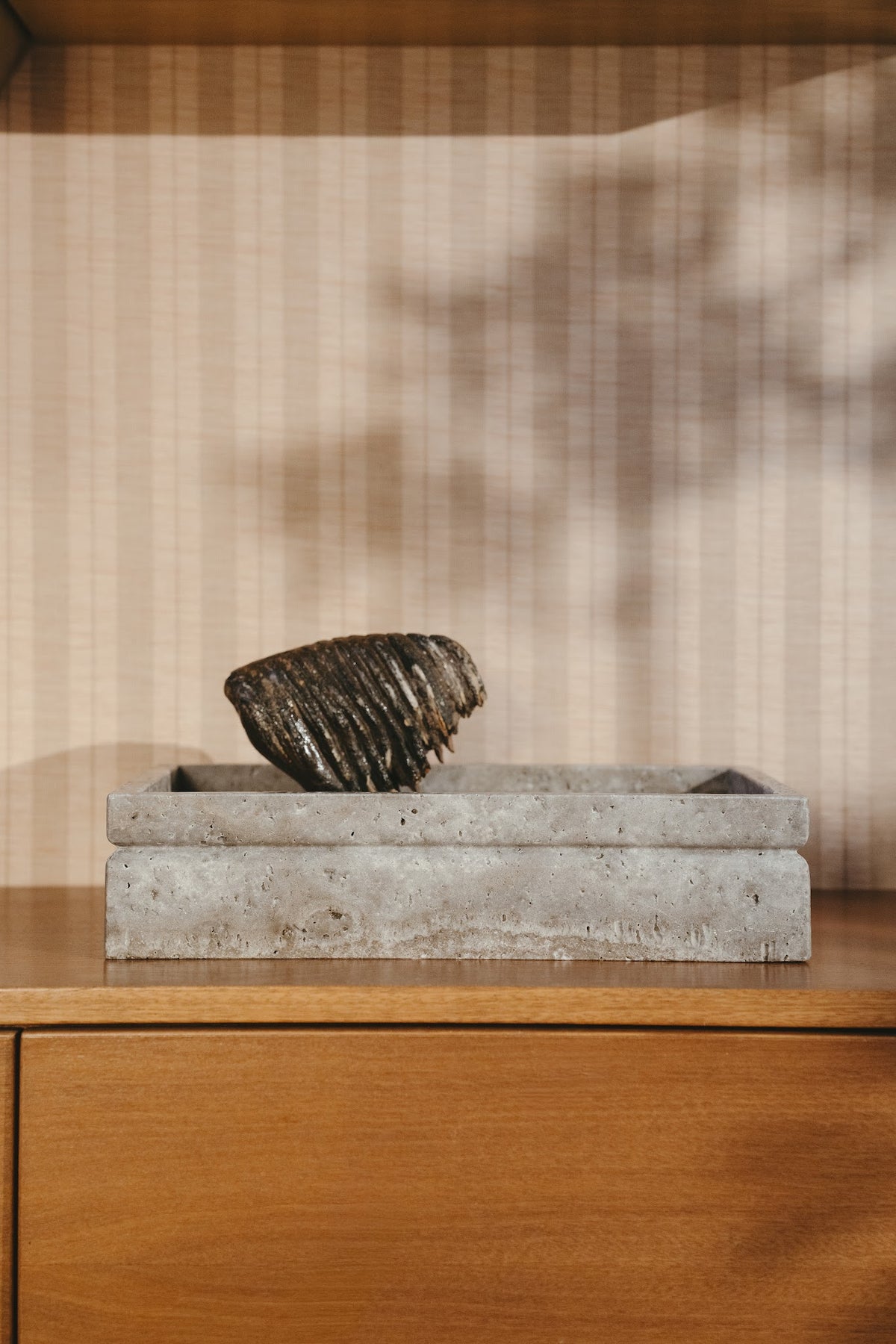 Silver travertine Tray urn with a natural stone on a wooden sideboard